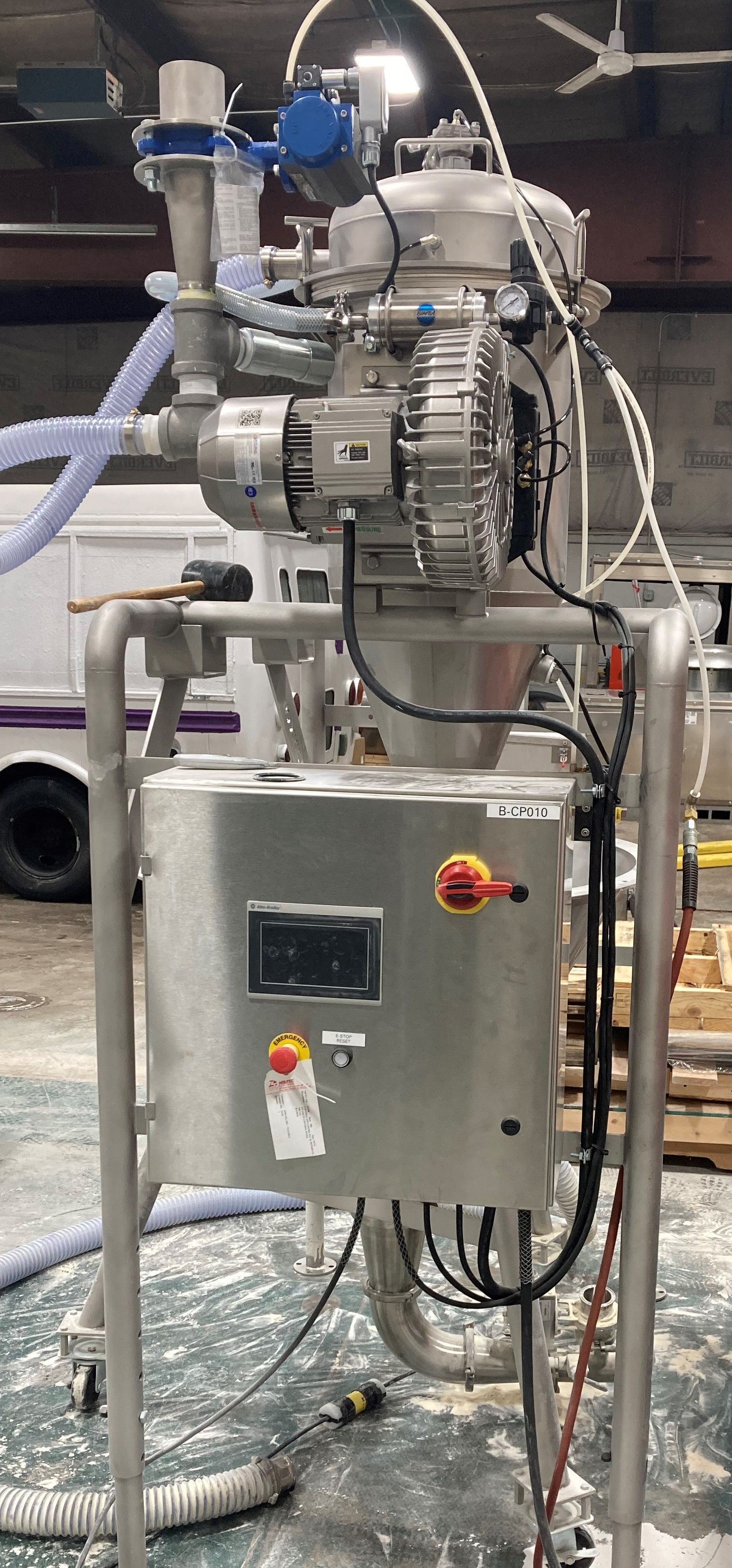 A stainless steel machine is sitting on the floor in a warehouse.
