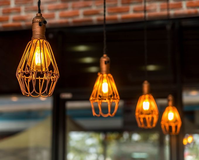 A row of hanging lights with a brick wall in the background.
