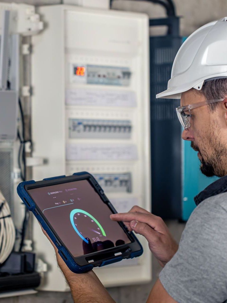 A man wearing a hard hat is using a tablet computer.
