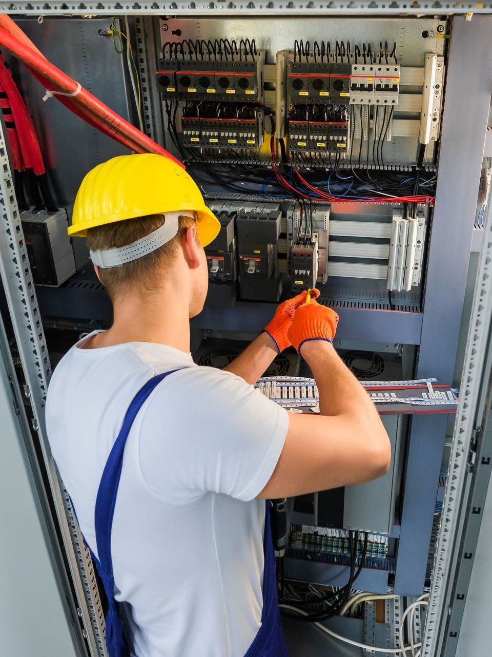 A man wearing a hard hat is working on an electrical box