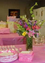 Pink gift boxes and a colorful flower arrangement on a decorated table for a celebration
