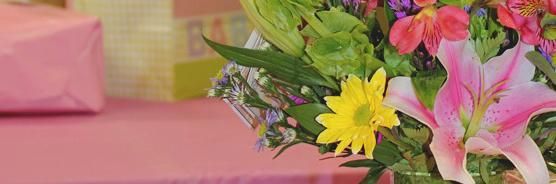Pink gift bag and colorful flowers on a pink table