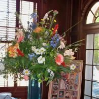 Tall floral arrangement with colorful flowers in a room by windows