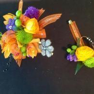 Two colorful floral hair clips on a black background, featuring yellow, purple, green, and orange accents