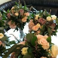 Floral wreaths of peach and cream roses with greenery hanging against a dark background