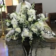 White floral funeral arrangement on a stone altar in a church sanctuary