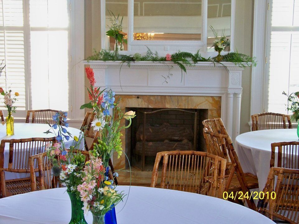 Bright dining room with a white fireplace, floral centerpiece, and round tables set for an event