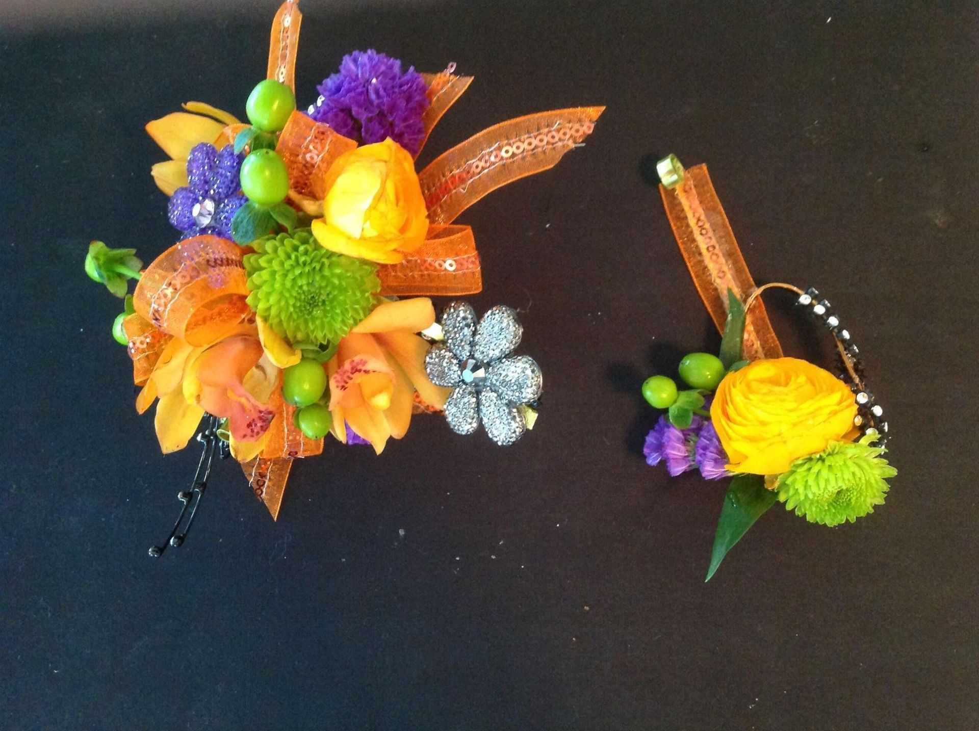 Colorful floral craft arrangements with orange, purple, green, and yellow accents on a black background