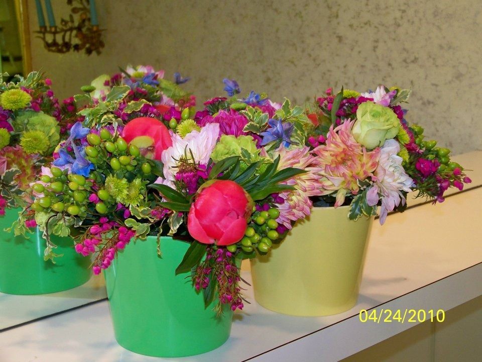 Colorful flower bouquets in pastel buckets on a table, with a date stamp in the corner