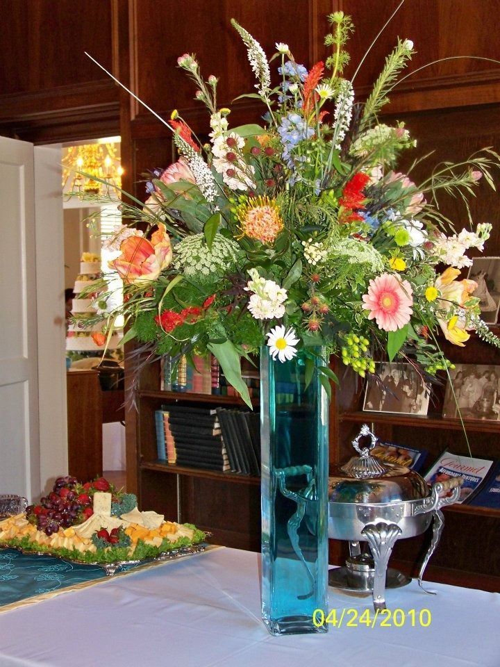 Tall blue vase with a colorful floral arrangement on a table indoors