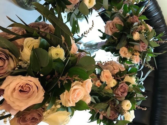 Close-up of pastel rose bouquets with greenery and candles on a table
