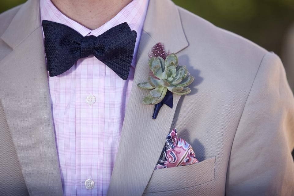 Beige suit with navy bow tie, succulent boutonniere, and patterned pocket square.