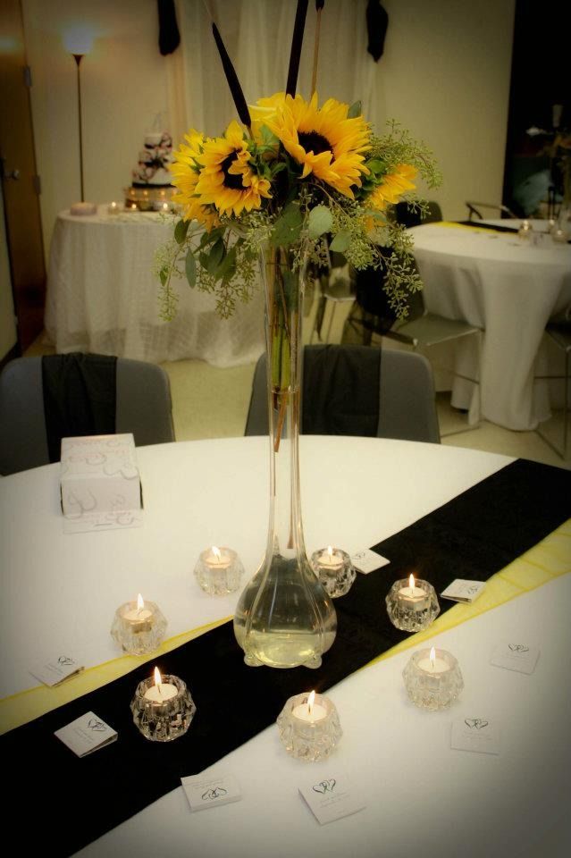 Sunflower centerpiece on a banquet table with white tablecloths and candles in a softly lit room
