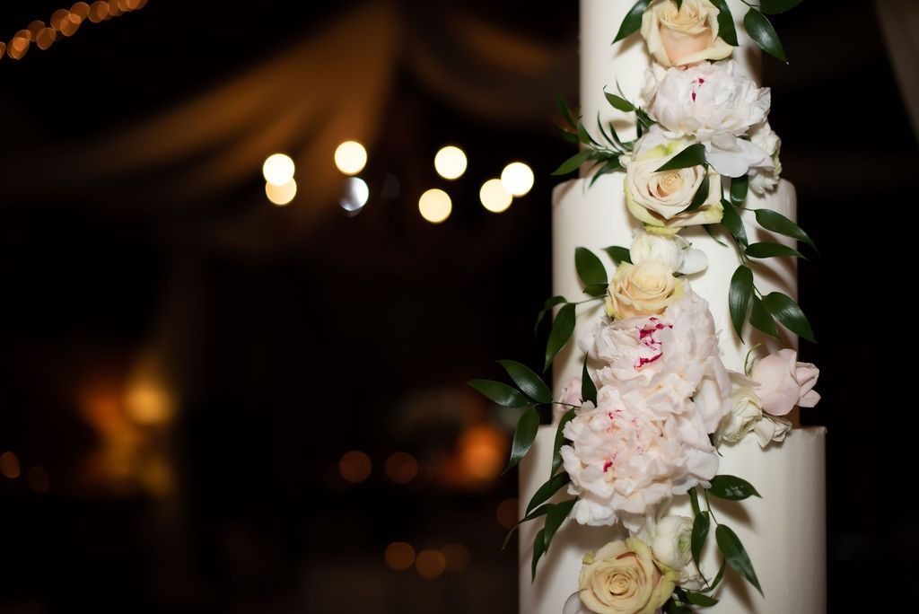 White floral wedding decor wrapped around a pillar with warm lights in the blurred background