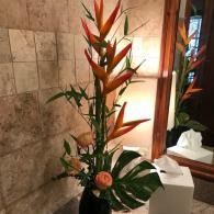 Tropical flower arrangement with orange bird-of-paradise and pink blooms in a tiled indoor setting