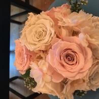 Bouquet of pale pink and cream roses with greenery in a decorative arrangement