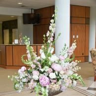 Large pastel floral arrangement on a table in a hotel lobby or reception area