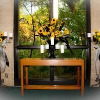 Flower arrangement with sunflowers on a wooden console table in a windowed room
