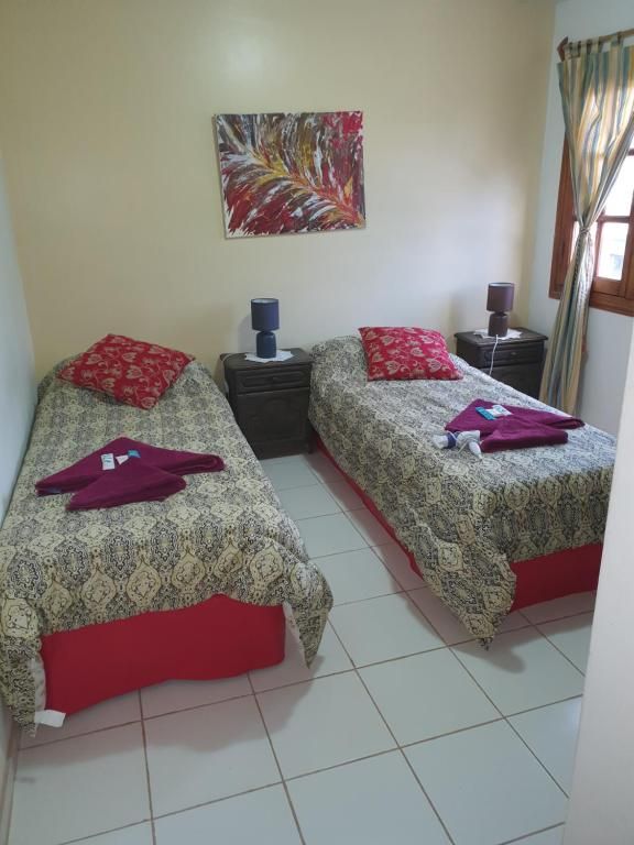 Dos camas individuales con colchas estampadas y detalles en rojo en un dormitorio pequeño.