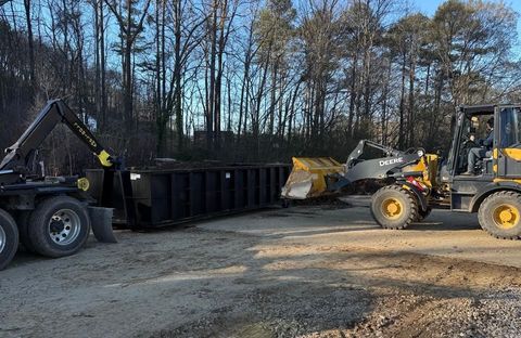 A dump truck and a front end loader are parked in a dirt lot.