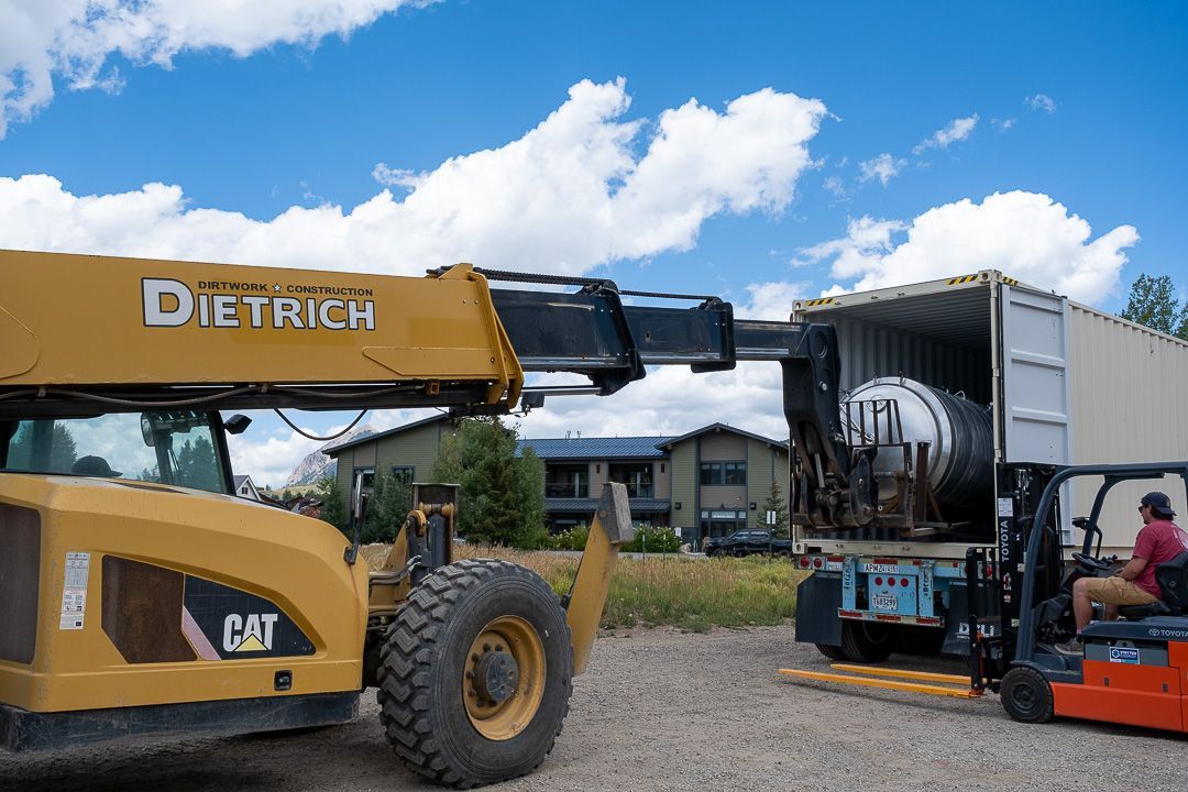 A cat forklift is loading a container into a truck.