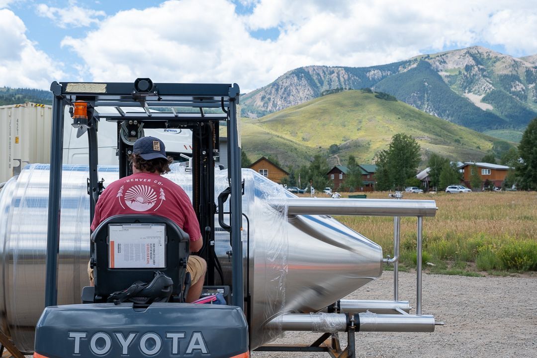 A man is driving a toyota forklift in a field with mountains in the background.