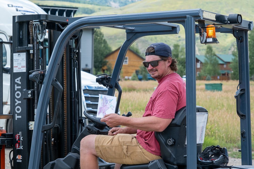 A man is sitting in a forklift in a field.