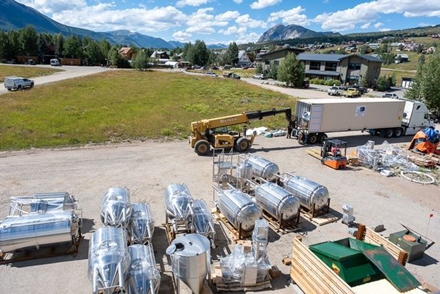 A lot of stainless steel tanks are sitting on pallets in a parking lot.