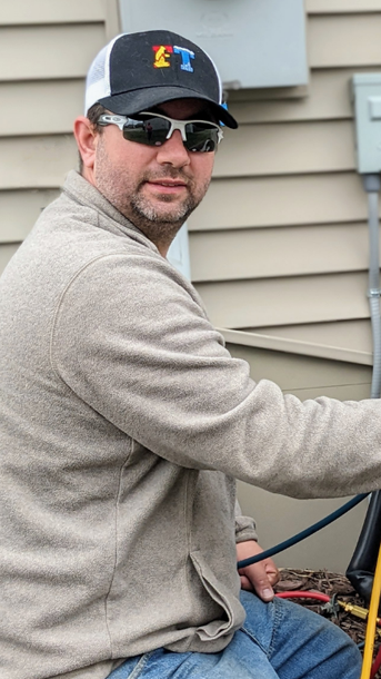 Full Time Heating & Cooling | A man wearing a hat and sunglasses is sitting in front of a house.