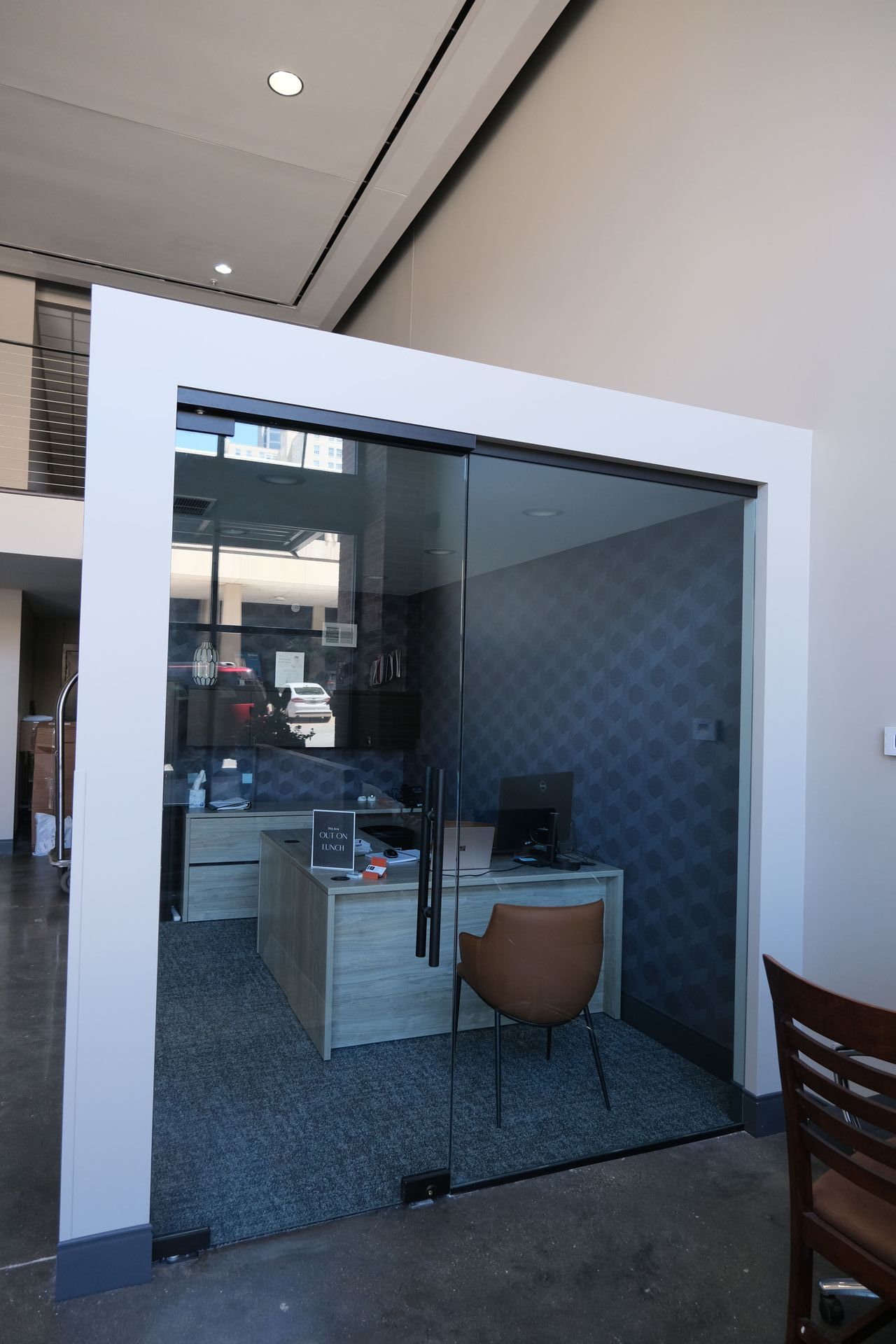 A small office with a desk and chair inside of a glass wall.