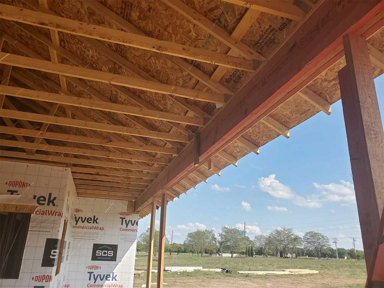 The ceiling of a building under construction with a blue sky in the background.