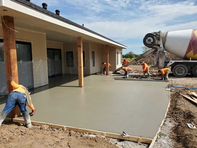 A group of construction workers are working on a concrete driveway.