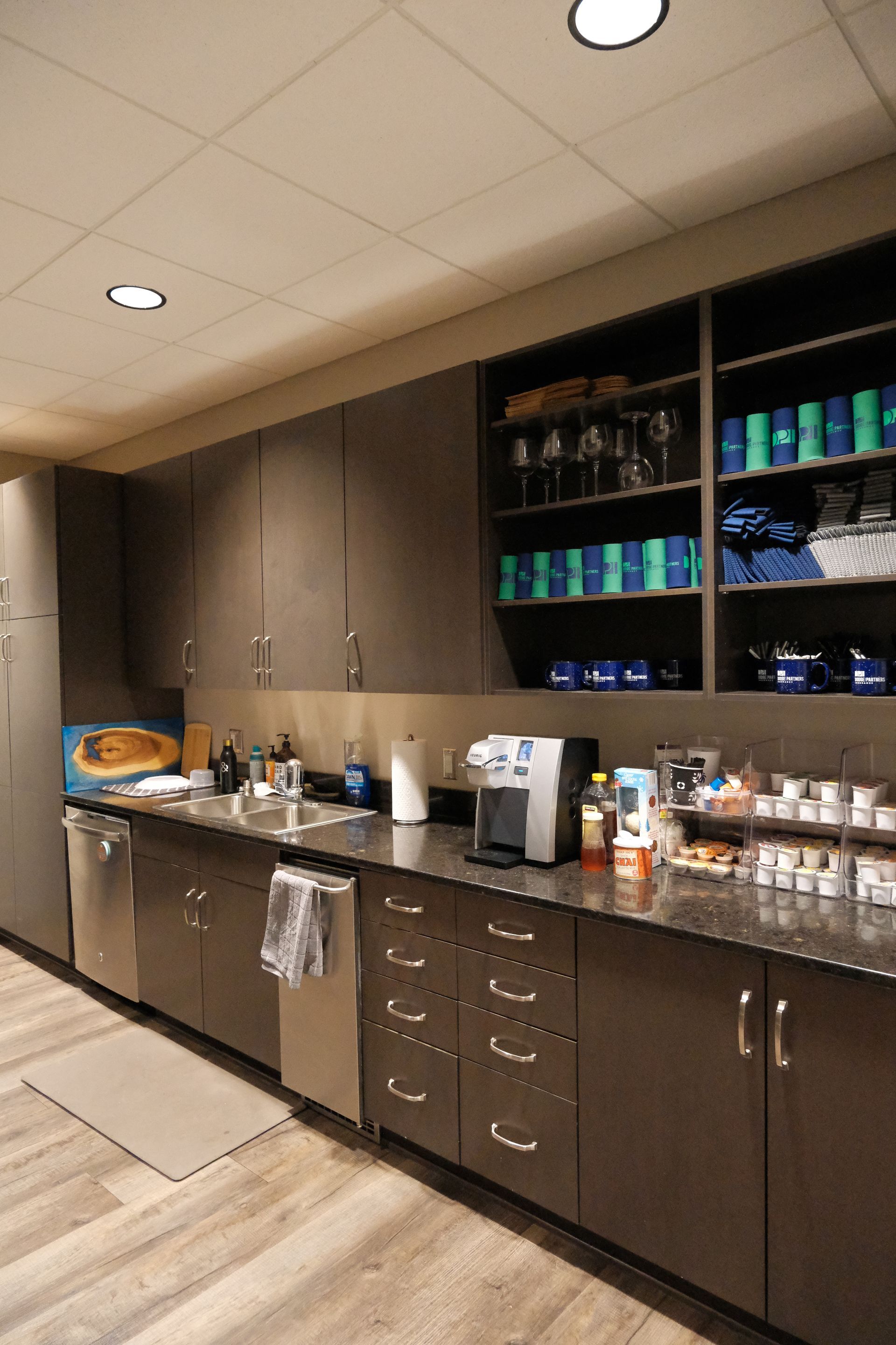A kitchen with a sink , dishwasher , and shelves.