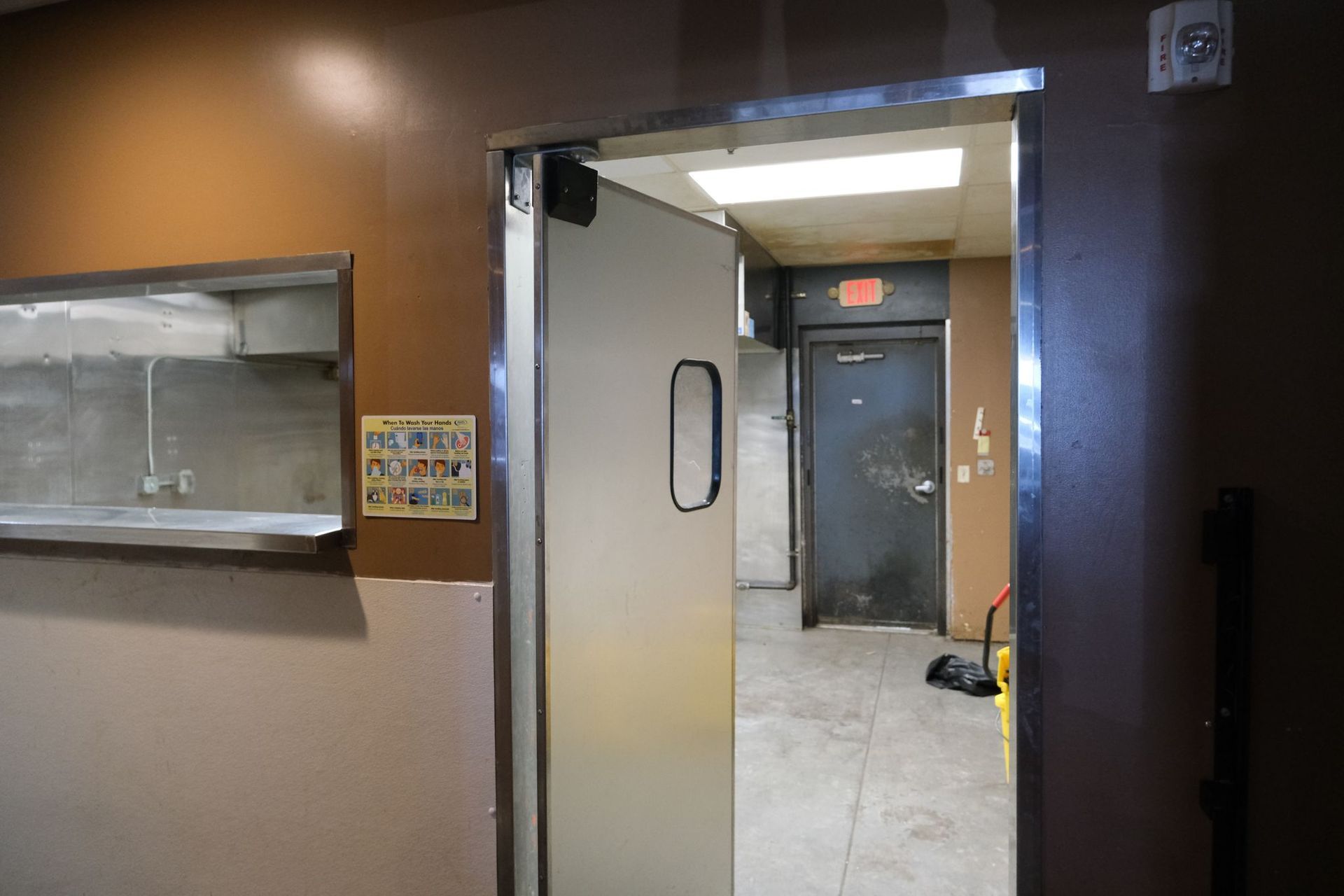 Doorway leading to a back room, with a commercial kitchen counter and metal door.