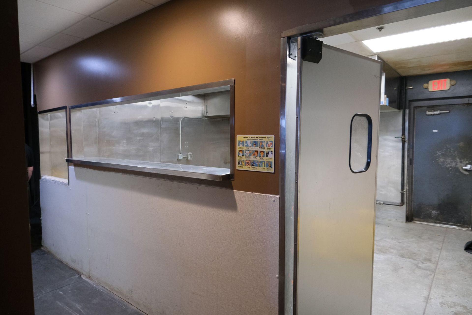 Interior with service window, walk-in door, and dark door to a back area. Brown and beige walls.