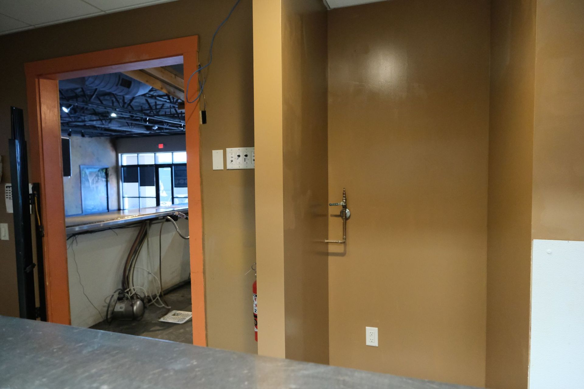 A doorway with an orange frame leads to a bar area. Next to it is a brown door.