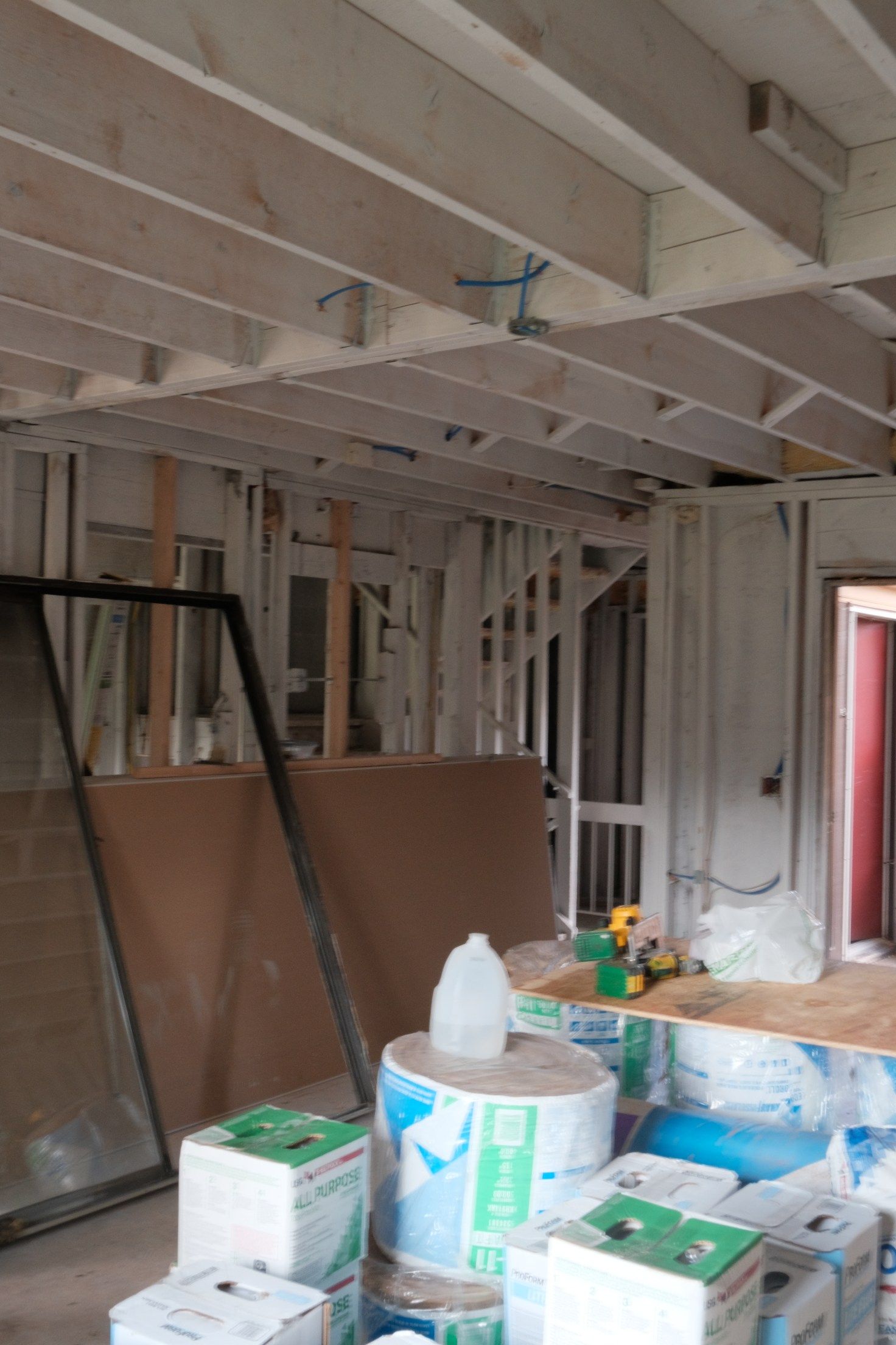 Interior view of a construction site with exposed wooden beams, studs, and insulation materials.