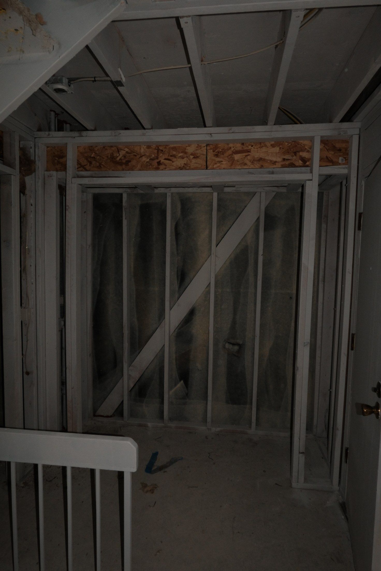 Interior framing of a closet; wooden studs and a diagonal support beam.