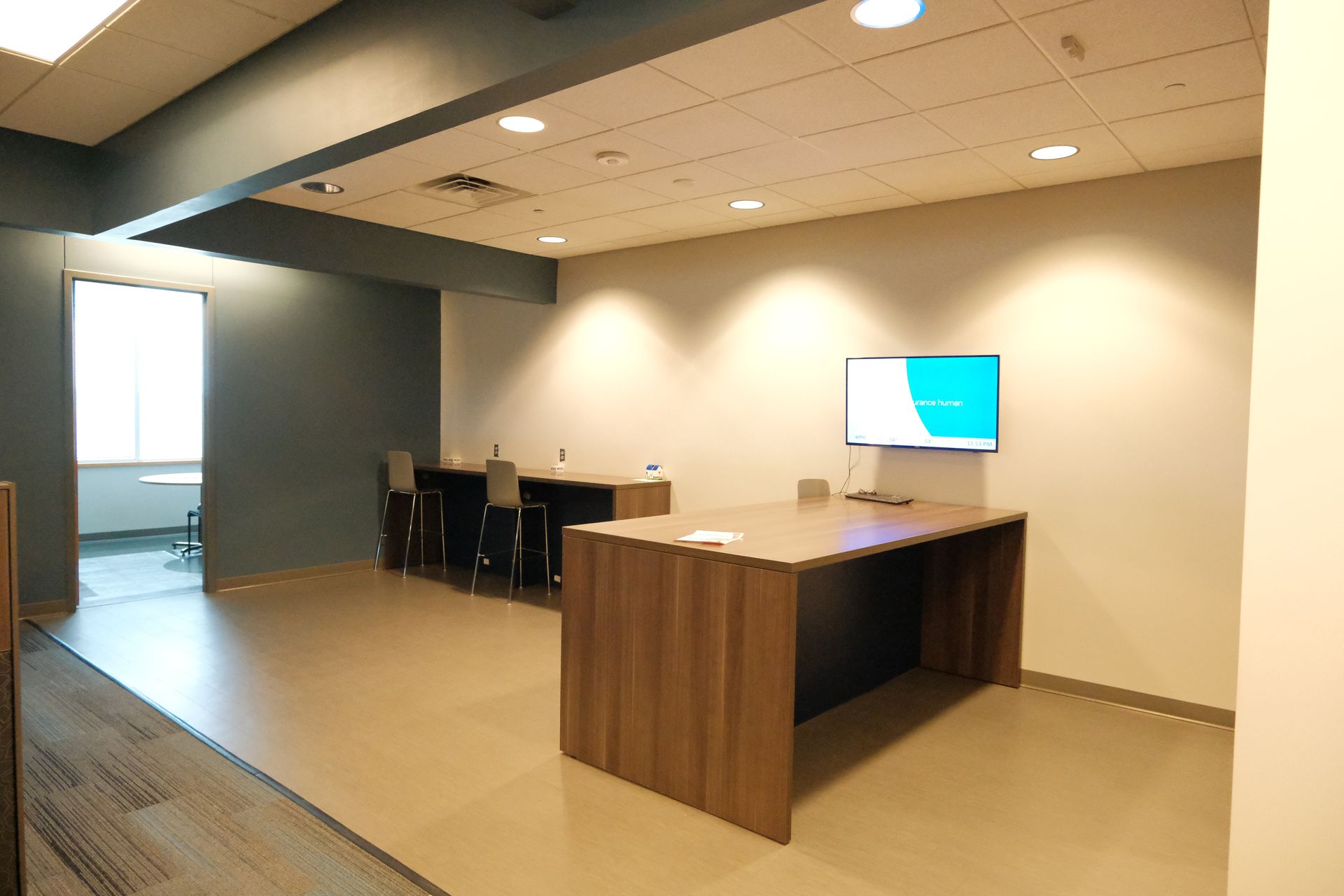 A large room with a table and a television on the wall.