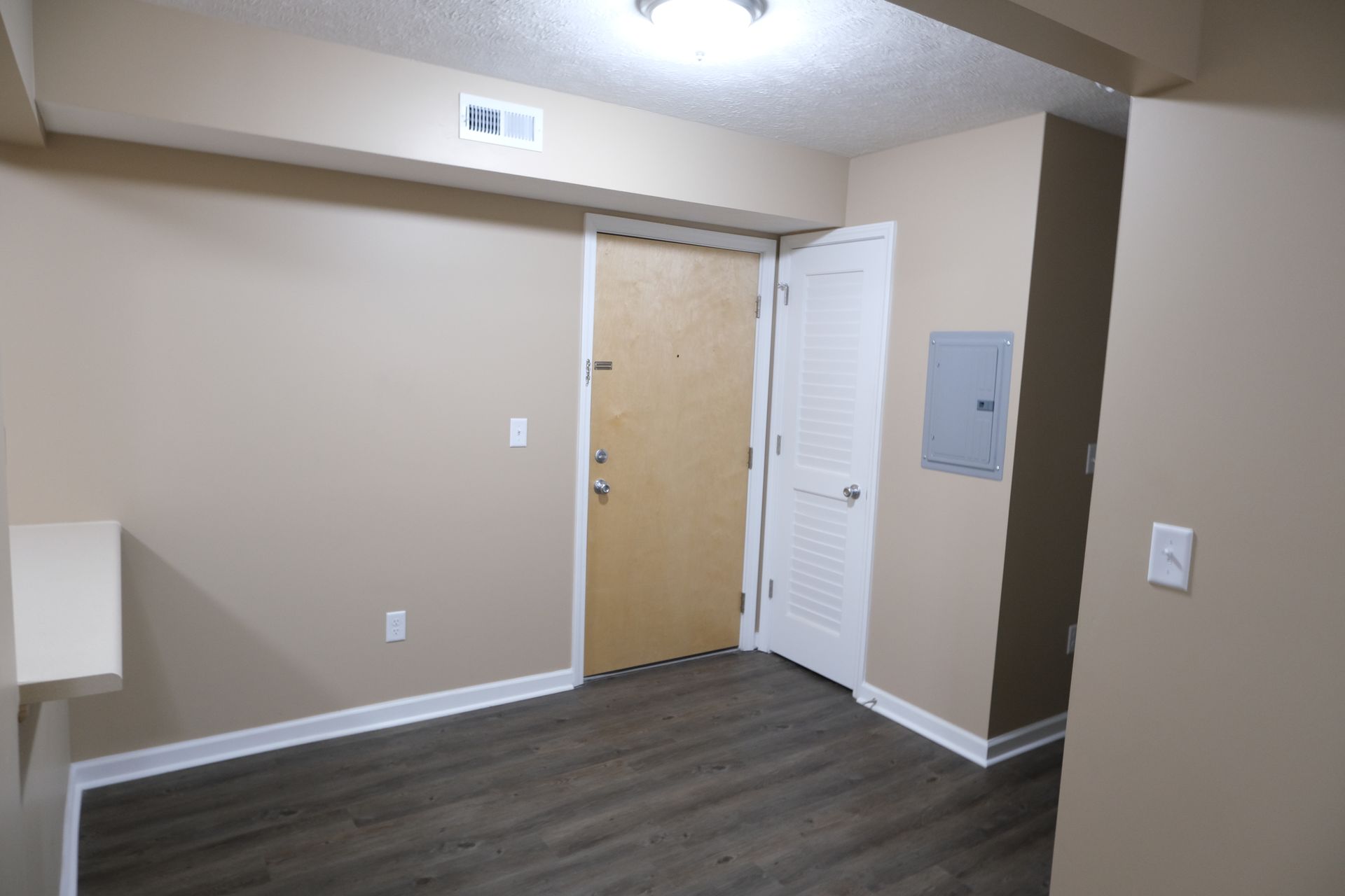 An empty room with a door and a light switch on the wall