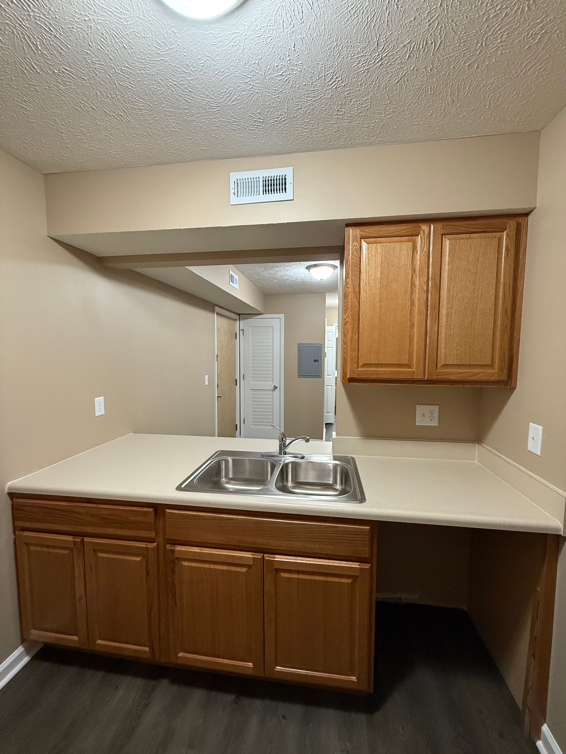 An empty kitchen with two sinks and wooden cabinets