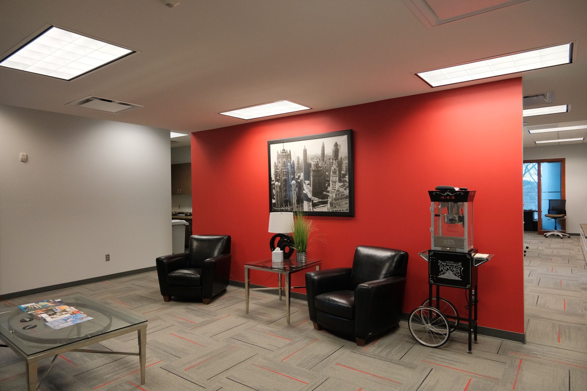 A room with red walls and black chairs and a popcorn machine