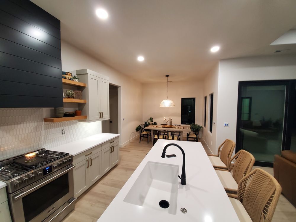 A kitchen with white cabinets , stainless steel appliances , a sink and a stove.