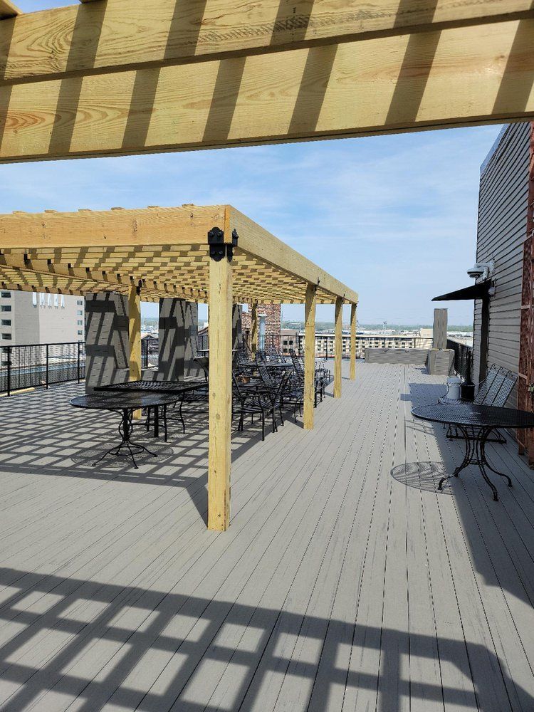 A wooden deck with tables and chairs under a pergola