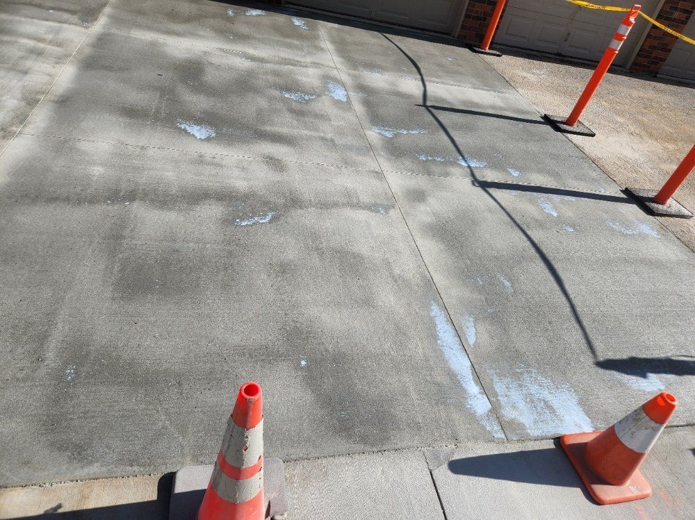 Two orange and white traffic cones are sitting on a concrete surface.