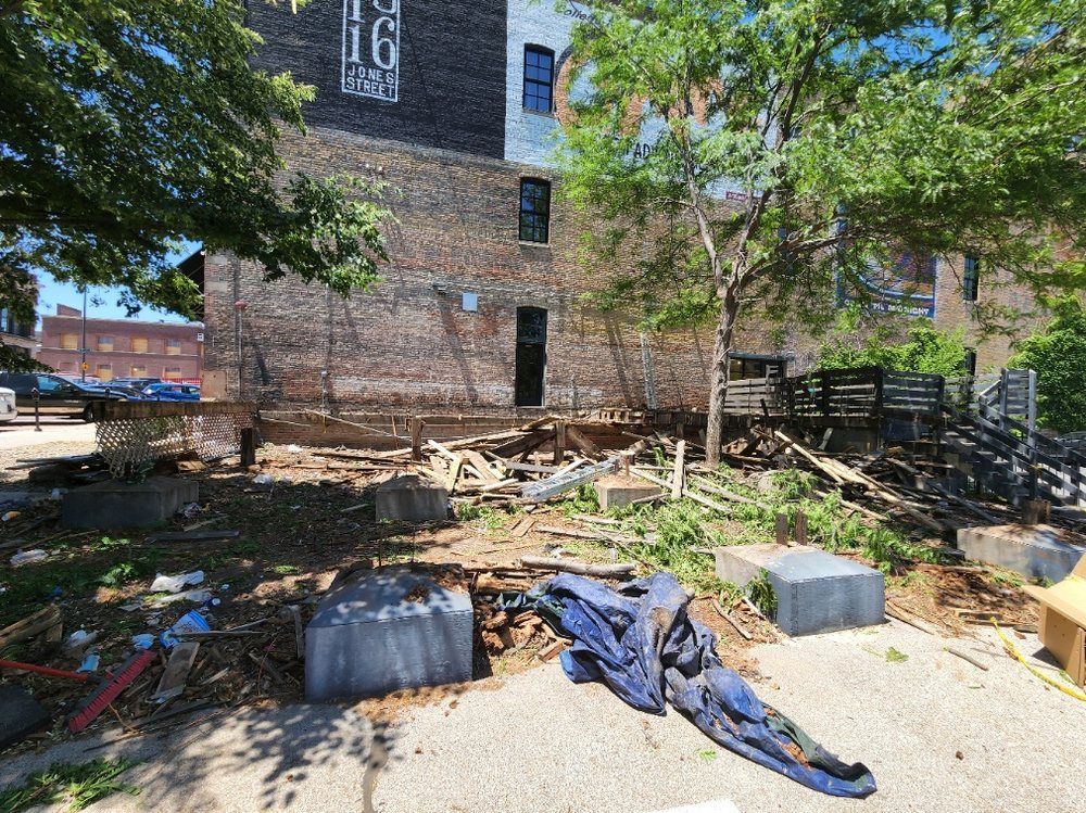 A construction site with a building in the background and a blue tarp on the ground.