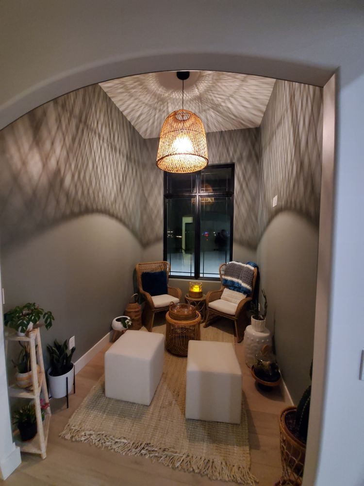 A living room with chairs , ottomans , a table and a window.