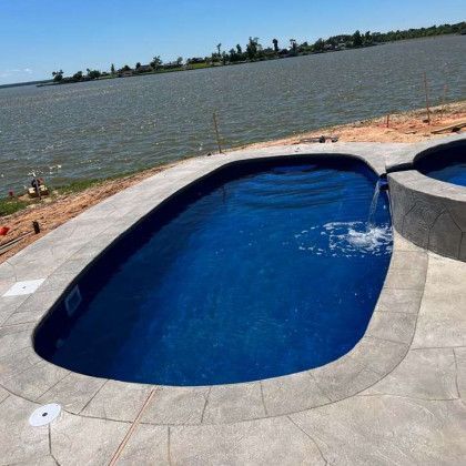 A large swimming pool is sitting next to a body of water.