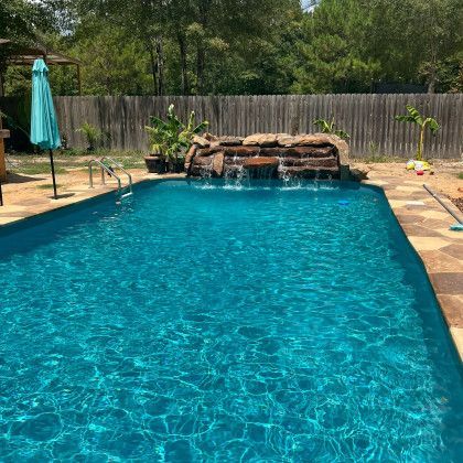 A large swimming pool with a waterfall in the backyard.