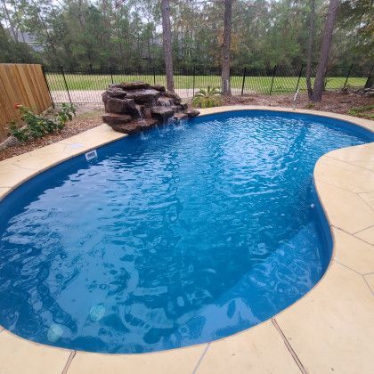 A large swimming pool with a waterfall in the middle